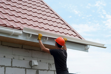 Man installing gutters on home